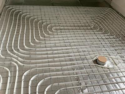 De vloerverwarming, slakkenhuispatroon op isolerende tackerplaat.