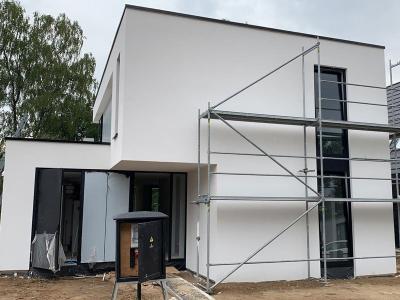 De strakke staalframewoning met isolerende gevelafwerking.