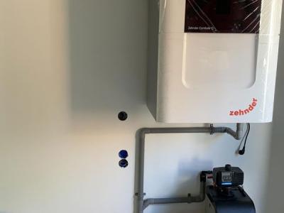 De Zehnder ComfoAir Q450 (ventilatie met warmteterugwinning), daaronder de waterontharder.